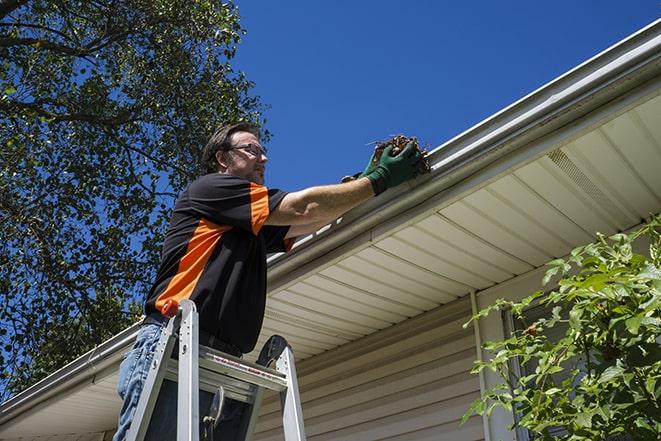 repairing a damaged rain gutter on a sunny day in Ashland